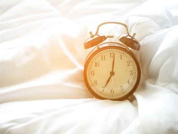 Relógio despertador na cama de manhã com luz solar — Fotografia de Stock