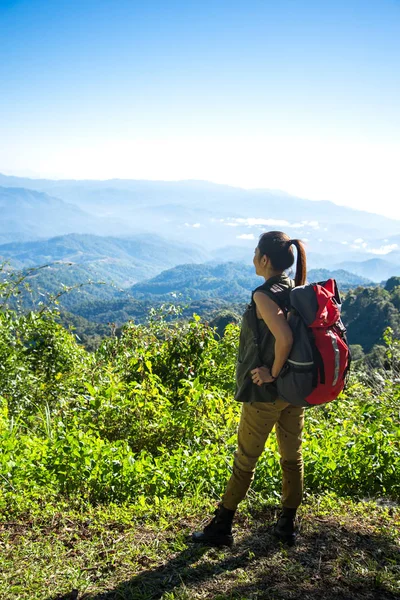Hiker woman look binoculars on the mountain, background blue sky, Thailand, select and soft focus