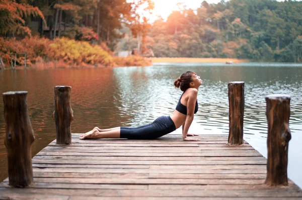 Frisk kvinna utövar yoga på bryggan i naturen — Stockfoto