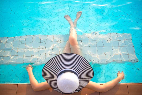 Jovem mulher de chapéu grande relaxante na piscina — Fotografia de Stock