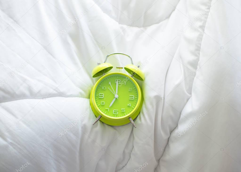 Alarm clock on bed in morning with sun light, Greenery ,soft and select focus