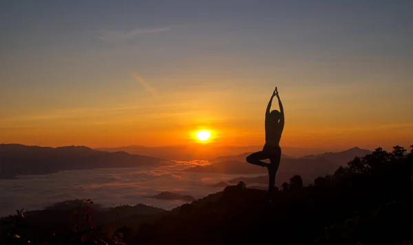Siluet genç kadın gün doğumunda dağda yoga yapıyor. — Stok fotoğraf