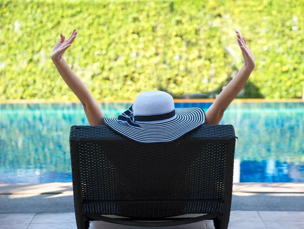 Jovem mulher de chapéu grande relaxante na piscina, verão — Fotografia de Stock