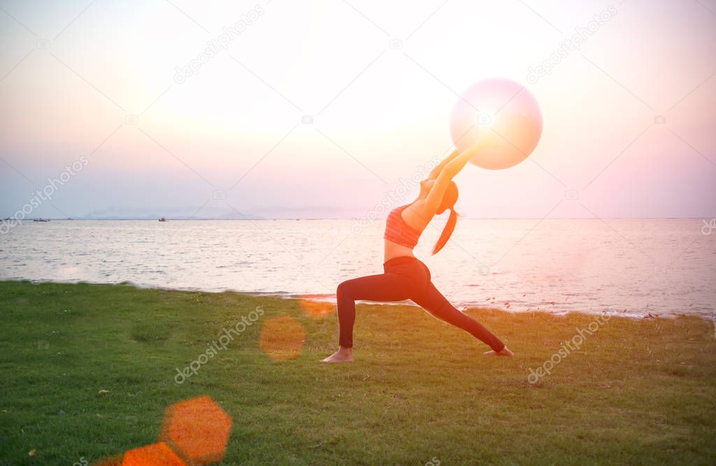 Silhouette yoga ball and pilates ball yong woman in the beach sunset background