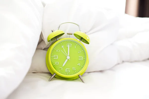 Alarm clock on bed in morning with sun light, Greenery ,soft and select focus