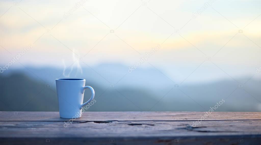 Cup with coffee on table over mountains landscape with sunlight. Beauty nature background