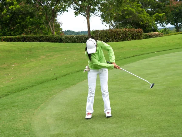 Mulher sorrindo jogador de golfe colocando com sucesso bola em verde, bola caindo no copo , — Fotografia de Stock