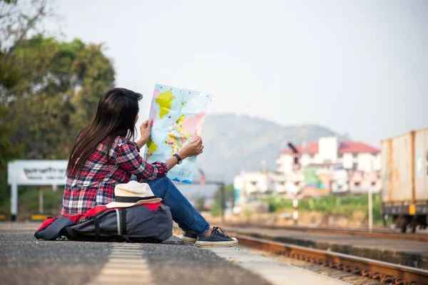 Traveler women wearing backpack holding map, waiting for a train.