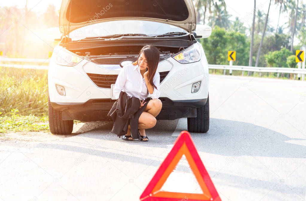 Business woman with a broken car calling for assistance