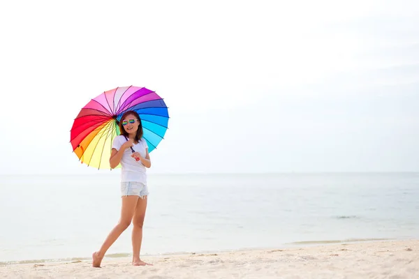 Fiatal nők ugrás esernyő és boldog a strandon. Utazás, nyaralás. Szabadság-fogalma — Stock Fotó