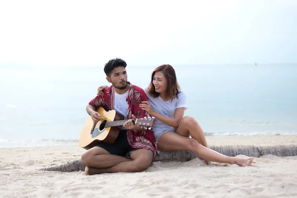 Niedliche hispanische Paar spielt Gitarre Ständchen am Strand in Liebe und Umarmung — Stockfoto