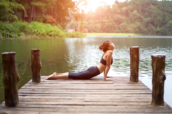 Femme saine pratiquant le yoga sur le pont dans la nature — Photo