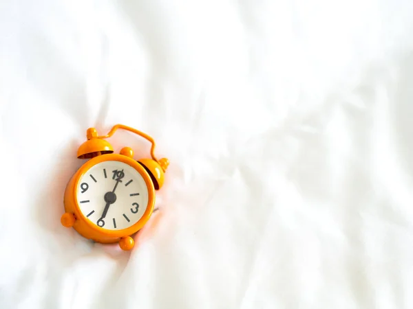 Relógio despertador na cama de manhã com luz solar — Fotografia de Stock