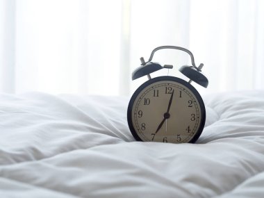 Sabah güneş ışığı ile yatakta çalar saat