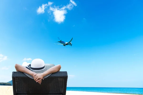 Mujer joven relajarse y ver el avión en la hermosa playa —  Fotos de Stock