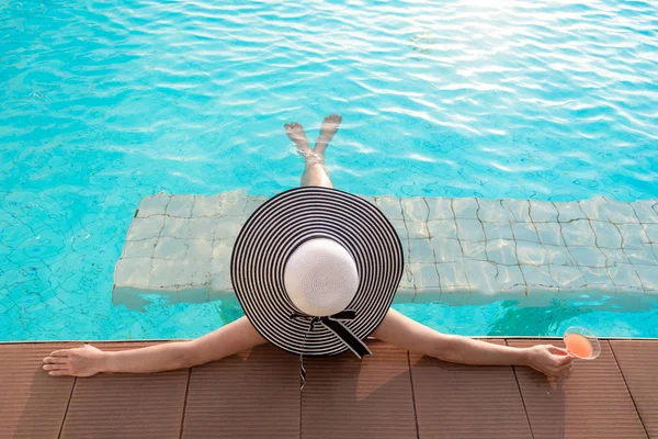 Jovem mulher de chapéu grande relaxante na piscina, perto do mar ao pôr do sol — Fotografia de Stock