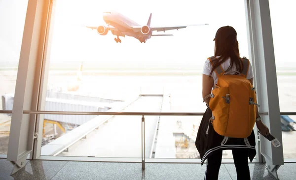 Mujer viajera ver el avión en la ventana del aeropuerto —  Fotos de Stock