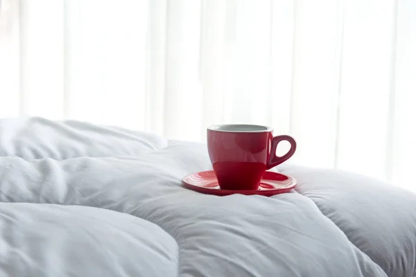 Café frais du matin en tasse rouge sur le lit . — Photo