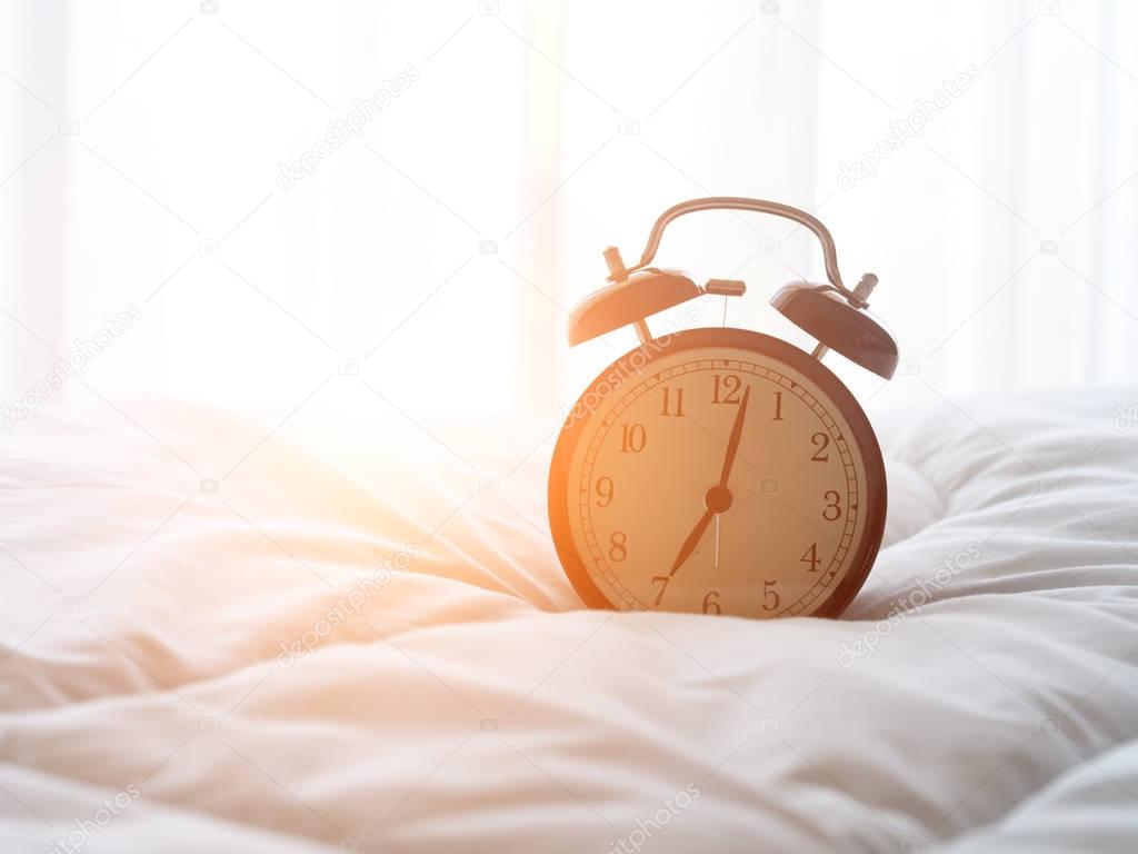 Alarm clock on bed in morning with sun light
