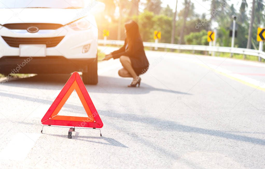 Business women driver changing tyre on her broken car