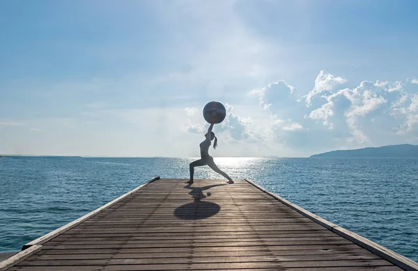 瑜伽球，普拉提球在海滩日出背景的年轻女子 — 图库照片