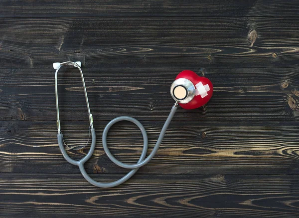 Un solo corazón rojo amor forma mano ejercicio pelota con vendaje MD médico médico estetoscopio viejo fondo de madera — Foto de Stock