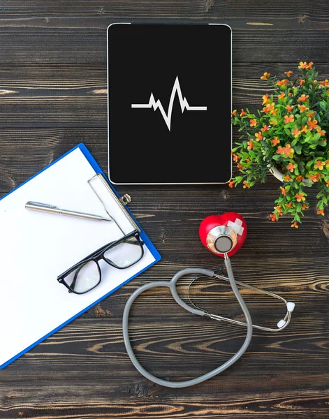 Un estetoscopio médico cerca de un portátil en una mesa de madera — Foto de Stock