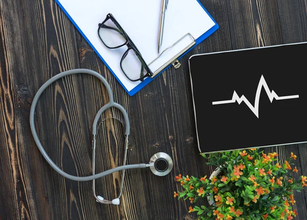 Un estetoscopio médico cerca de un portátil en una mesa de madera — Foto de Stock