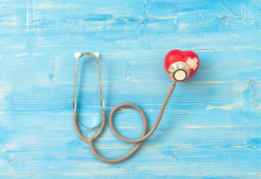Bir tek tek başına kırmızı kalp aşk şekli el egzersiz topu bandaj Md Medikal ile doktor doktor stetoskop mavi ahşap arka plan