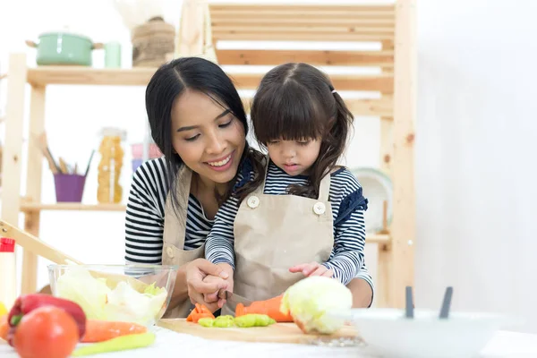 母亲和孩子的女孩烹饪和切割蔬菜在厨房 — 图库照片