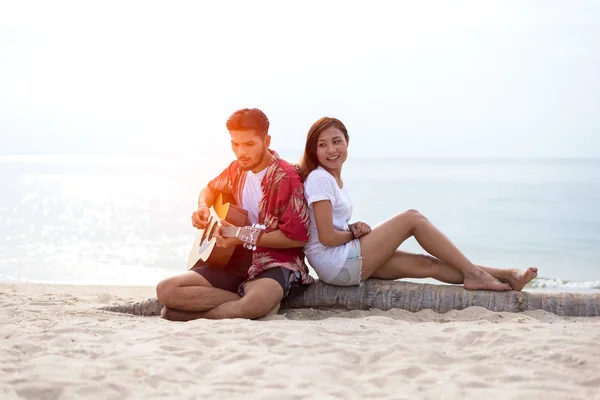 Linda pareja hispana tocando la guitarra serenata en la playa en el amor y abrazo —  Fotos de Stock