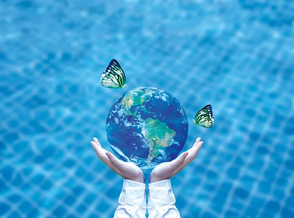 Mariposa bebiendo agua de globo azul en la mano. Concepto de ahorro de agua, elemento de imagen suministrado por la NASA — Foto de Stock