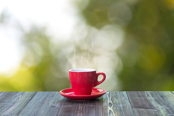 Heißen Kaffee mit in roter Tasse auf Holztisch und Natur Bokeh Hintergrund — Stockfoto