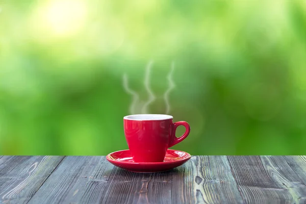 Heißen Kaffee mit in roter Tasse auf Holztisch und Natur Bokeh Hintergrund — Stockfoto