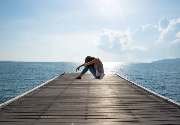 Denize sıfır, yalnız ruh köprüde oturan genç çekici kadın — Stok fotoğraf