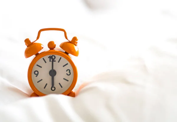 Reloj despertador en la cama por la mañana con luz solar —  Fotos de Stock