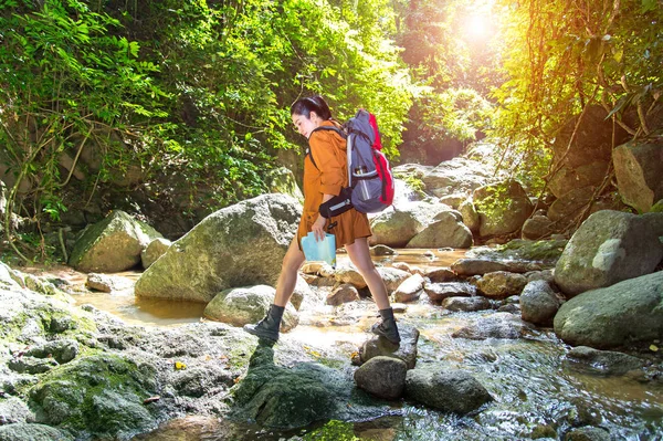Women traveler with backpack checks map to find directions in water fall and forest nature — Stock Photo, Image