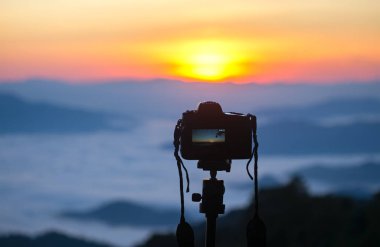 Açık havada bir tripod üzerinde kamera closeup. Arka plan manzara odak dışı. Kavram seyahat
