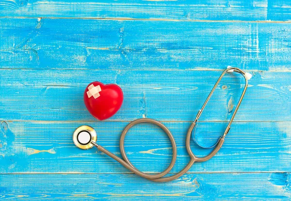 Un solo corazón rojo amor forma bola de ejercicio mano sola con vendaje MD médico médico estetoscopio fondo de madera azul. Concepto saludable . — Foto de Stock