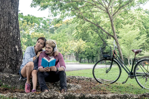 Casal feliz lendo um livro enquanto ouve música em um parque, tom vintage — Fotografia de Stock