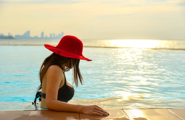 Feliz sorrindo mulher asiática com chapéu de palha relaxar e luxo na piscina, pôr do sol fundo. Conceito de Verão — Fotografia de Stock