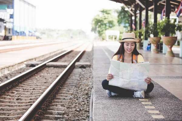 旅行者や観光アジアの若い女性のバックパックを保持マップを着て、電車を待っている。旅行のコンセプト. — ストック写真