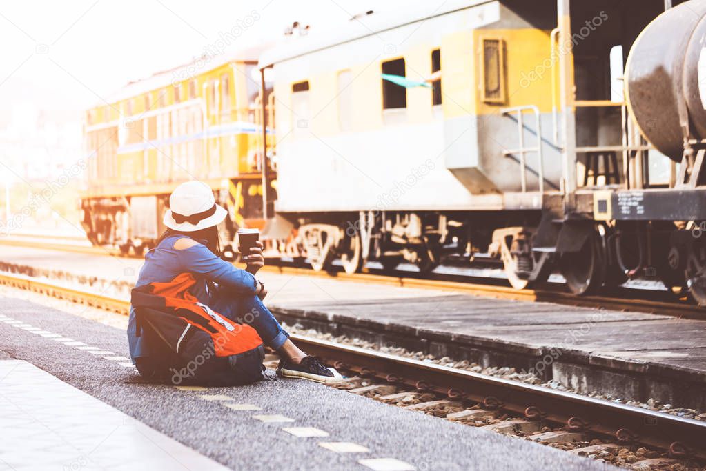 Traveler and tourist women wearing backpack holding map and drinking coffee, waiting for a train, vintage tone. Travel Concept.