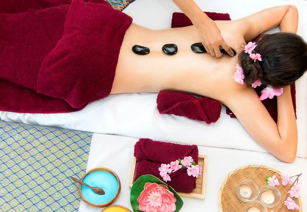 Asia beauty woman lying down on massage bed with traditional hot stones along the spine at Thai spa and wellness center, so relax and lifestyle.  Healthy Concept