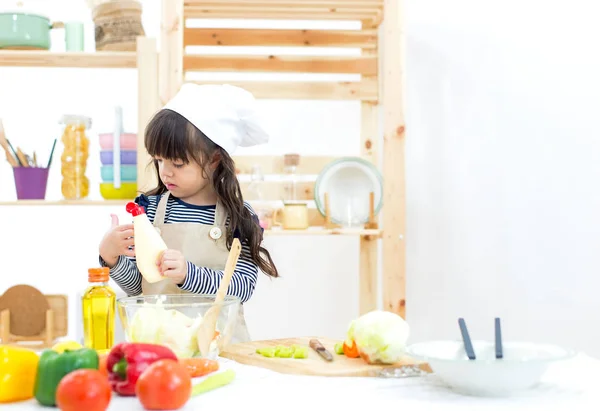 Bella ragazza asiatica bambino rendendo insalata di verdure in cucina — Foto Stock