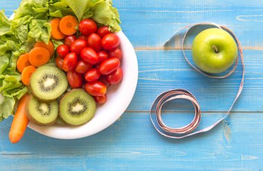 Sağlıklı yaşam için ölçüm bandı ile kadın diyet sebze taze, yeşil elma ahşap üzerinde mavi. Sağlıklı kavramı.