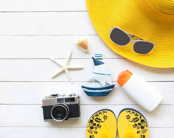 Letní móda žena žluté velké čepice a doplňky na pláži. Tropické moře. Neobvyklý pohled shora, dřevo bílé pozadí. Letní koncept. — Stock fotografie