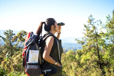 Sırt çantası ile kadınlar uzun yürüyüşe çıkan kimse harita yol tariflerini bulma ve dağ ve orman en vahşi alanında dürbün bakmak için denetler. Seyahat kavramı