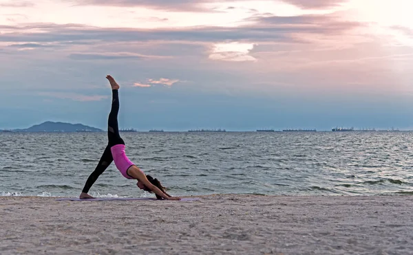 Silhouette style de vie jeune femme exercice vital méditer et pratiquer la balle de yoga sur la plage au coucher du soleil. Concept sain . — Photo