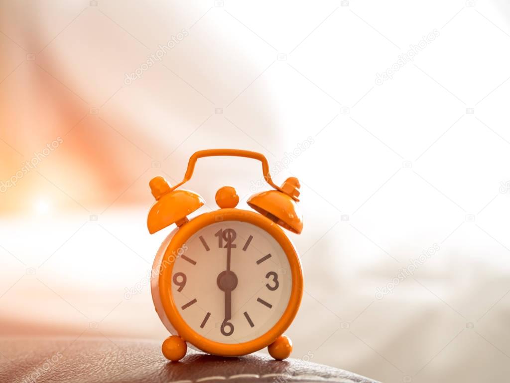 Orange Alarm clock on bed in morning with sun light